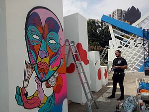 Seorang seniman saat membuat mural bertema badminton.