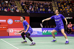 Hendra Setiawan/Mohammad Ahsan mengembalikan shuttlecock.